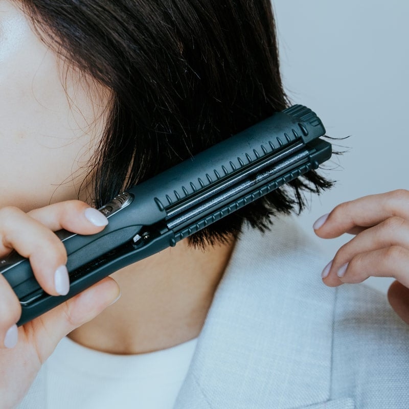 MAGNETHairProストレートアイロンを使用しスタイリングする女性の画像。